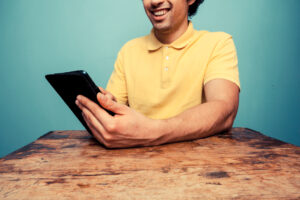 Young man at table reading on tablet